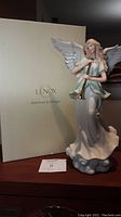 Porcelain angel figurine displayed next to its original Lenox box with branding visible.