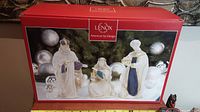 The set of three Lenox Three Kings nativity figurines displayed with original red box showing figurines in front of festive background.