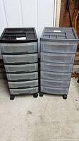 Full view of two rolling storage carts, one black and one gray with multiple translucent drawers, positioned side by side.