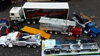 Overview of multiple toy rigs including white tow truck, GM trailer rig, red cab rig and others.