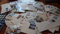 Wide view of assorted envelopes, postcards, and loose stamps spread on a table showing condition and quantity.