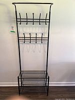 Front view of the black metal coat rack showing two rows of hooks and a lower storage rack.