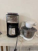 Cuisinart coffee maker with glass carafe alongside Bosch stand mixer Model 9406 on countertop