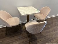 Three Structube cushioned dining chairs arranged around a small square white marble-top table on a dark wood floor