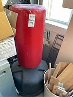 Front view of the red punching bag attached to a black weighted base, surrounded by miscellaneous items.