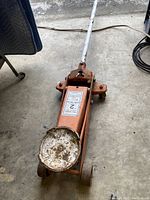 Top view of used orange Allied 2 ton hydraulic floor jack showing lifting saddle, handle, and wheels.