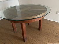 Full view of round wooden table with glass top showing legs and floor contact.