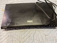 Top view of Samsung Ultra HD BluRay DVD player in black with visible Ultra HD logo and power cable