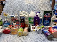 Full view of assorted cleaning products on blue quilted surface showing multiple brands and product types