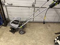 Side angle of Earthwise electric tiller showing handles, wheels, motor and blades.