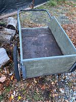 Side view of garden cart showing plywood bottom and sides, metal frame and spoked wheels.