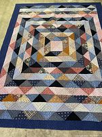 Top down view of the full quilt showing multi-colored geometric patchwork and blue border.