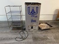 Full view of Little Chief electric smoker components including main smoker body with power cord, three wire shelves, and a metal stand.