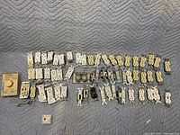Photo showing variety of standard electrical outlets, toggle switches, and rotary dimmer switch in original box laid out on quilted fabric