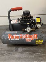 Side view of Senco Turbo HotDog II air compressor showing gray tank with orange/white label and black motor unit with red handle.
