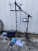 Entire karaoke bundle including microphone on stand, music stand, speaker, control panel, cables, and power adapter laid out outside.