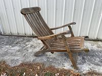 Side view of the teak folding lounge chair showing weathered teak wood and curved slats for seat and backrest.
