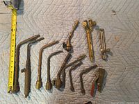 Overhead photo of all 12 torch attachments laid flat with a tape measure for scale, showing variety in lengths and types.