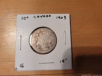 Reverse side of 1903 Canadian silver quarter showing crown-topped shield and maple leaf design.