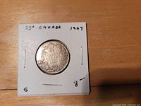 Reverse side showing Canadian coat of arms and surrounding wreath on 1907 Canadian 25 cent silver coin.