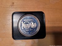 Photo of front side of 1974 Canadian Silver Dollar commemorative Winnipeg Centennial coin showing detailed imagery and inscriptions.