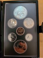 Photo of the full coin set in display case showing seven coins including the commemorative silver dollar with polar bear and aurora borealis design.