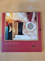 Front of commemorative coin set folder showing large coin window with gift box background and HO! HO! HO! text.