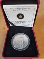 Photo of the coin in display case showing certificate and top view with dragon design.