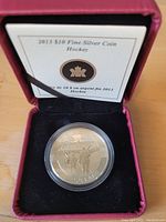 Front side of 2013 Canada $10 silver coin showing hockey scene inside presentation case with certificate of authenticity.