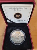 2013 Canada $10 Fine Silver Coin in capsule seated in red presentation case with black velvet interior and COA card visible inside case lid.
