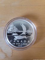 Obverse side of 2015 Canadian $50 silver coin showing a beaver swimming, detailed design with water splash and nature background, coin encased in clear plastic holder.