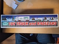 Box top showing branding and illustration of Hess toy truck and race cars in a winter scene