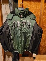 Front side of the New York Jets jacket showing team name embroidery, green and black colors, zipper, and ribbed cuffs.