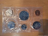 Front view of six Canadian coins in a transparent plastic holder showing detailed designs including large silver-colored dollar and smaller coins