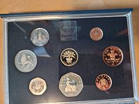 Front side of the coin set showing the reverse designs of the proof coins including various denominations and intricate designs representing UK symbols such as the lion and Britannia.