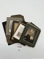 Photo showing stack of vintage photographs including cabinet cards with some photos mounted on black and green matte boards.