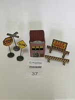 Overview of all items in the set including the tin fire station depot, three traffic signs, and two barricade signs.