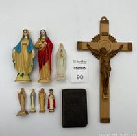Full lot showing all nine religious figurines, crucifix and prayer book arranged on white background.