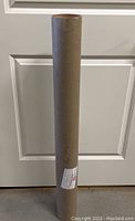 Photo of the brown cylindrical shipping tube containing the uncut sheet of NFL Cheerleaders trading cards.