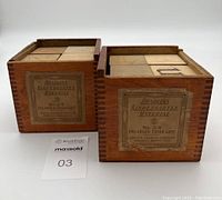 Two wooden crates of Milton Bradley Kindergarten blocks showing side labels with product details.