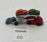 Silver car hauler loaded with four miniature diecast cars in orange, green, blue, and red colors.