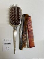 Set of two combs and one hairbrush laid flat showing combs' missing teeth and nylon bristles of brush