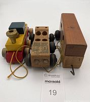 Top view of the entire three-piece Holgate wooden train set showing the locomotive and two attached cars on black wheels with pull strings.