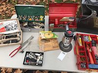 Full display of lot items on table including toolboxes, electric buffer, ratchet screwdriver, and assorted bits.