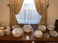 Wide shot of entire dinnerware collection on table including teacups, plates, bowls, serving bowls, and covered tureen