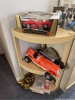 Photo showing boxed Bburago Mercedes-Benz 300 SL Touring 1957 model car on beige corner shelf, orange REMCO Shark racing model car, and a grey baseball hat