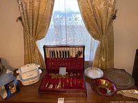 Wood box with Community tarnish-free gold flatware set open, also showing Corningware dishes, glass serving plates and bowls on table