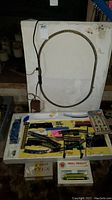Image of oval powered train track with wired controller and assorted track pieces.