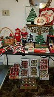 Full view of tables displaying various boxes of vintage glass ball ornaments, crocheted garlands, and Christmas figurines.