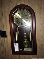 Front view of Waltham wall pendulum clock showing dial, weights, and pendulum in wooden case.